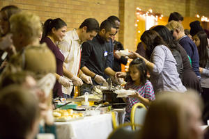 Families walk up to be served a meal at the 9th ACC Annual Thanksgiving potluck, Nov. 24